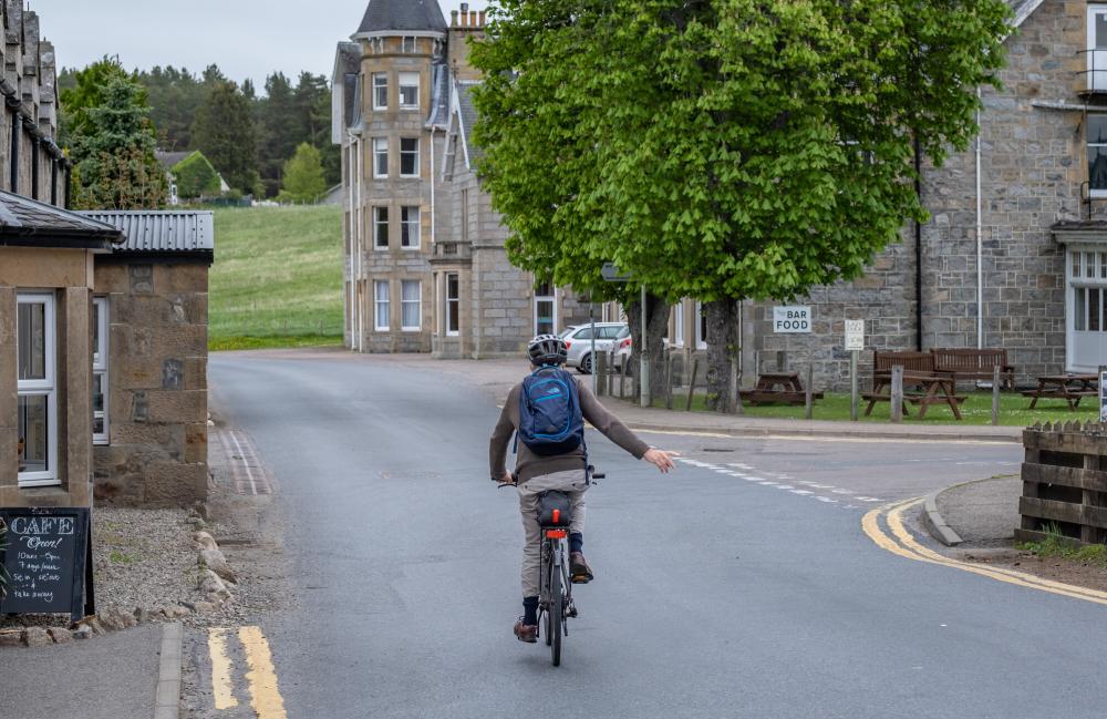 A cyclist signalling to turn right in Nethy Bridge
