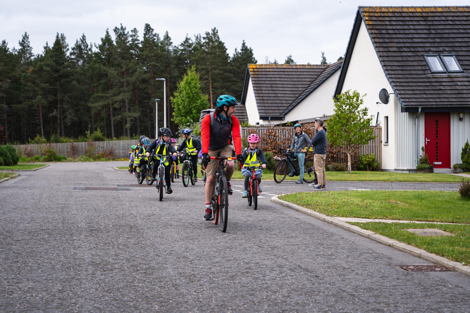 Adult leading a group of children on bikes