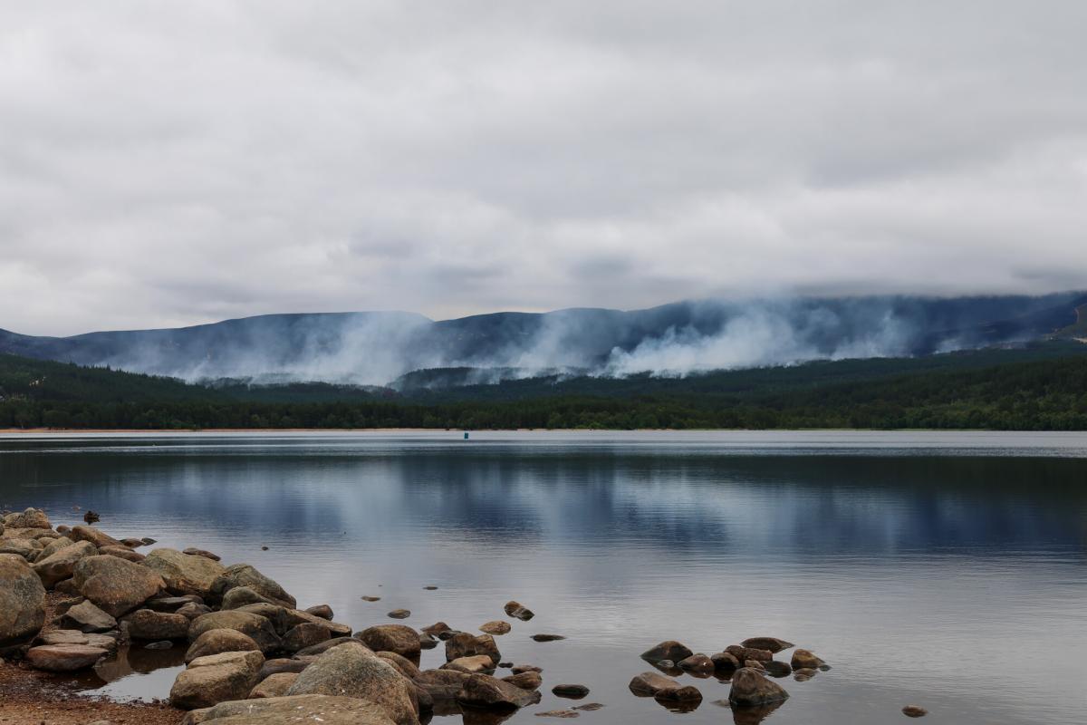 View across Loch Morlich with wisps of smoke rising in the distance from the Glenmore wildfire.
