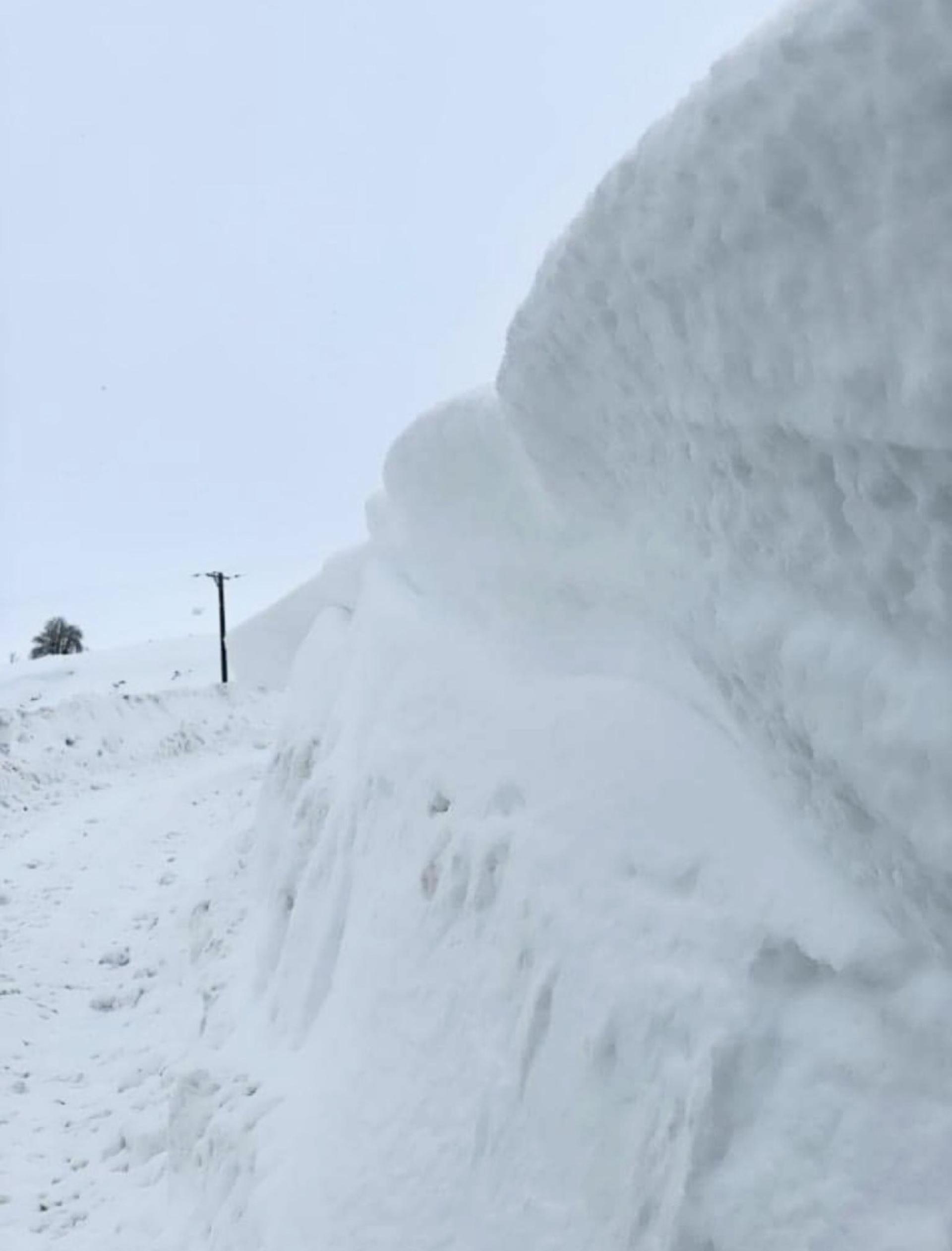 The side of a road in Glenbuchat with a wall of snow drifts 6ft high