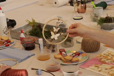 A hand holding an embroidery hoop with paper butterflies inside