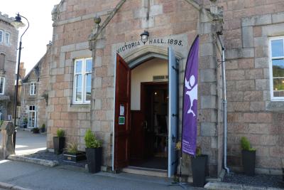Brick building with door open and purple flag on the right side