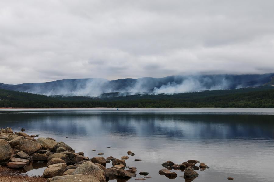 View across Loch Morlich with wisps of smoke rising in the distance from the Glenmore wildfire.