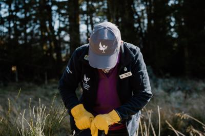 A person bending (top of cap in view) digging outside