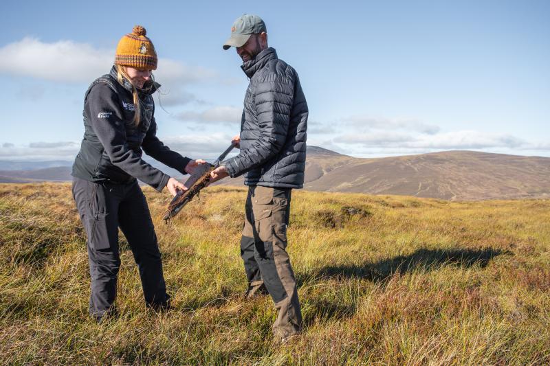 Members of the peatland team looking at a section of peat core taken from the bog