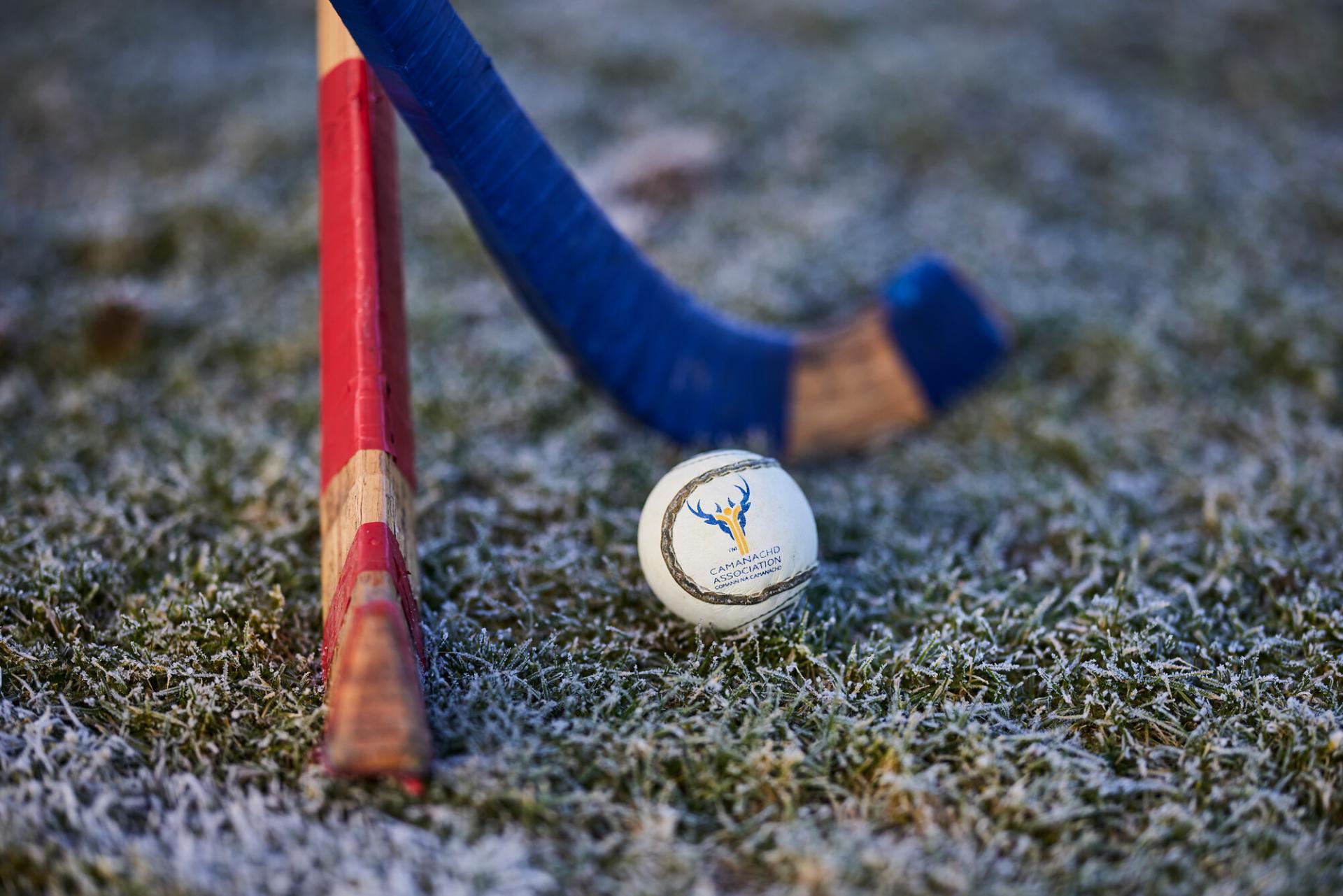 Two shinty sticks and shinty ball on frosty grass.