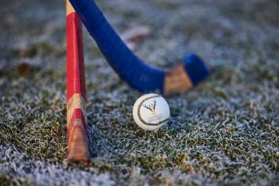 Two shinty sticks and ball on a frosty pitch