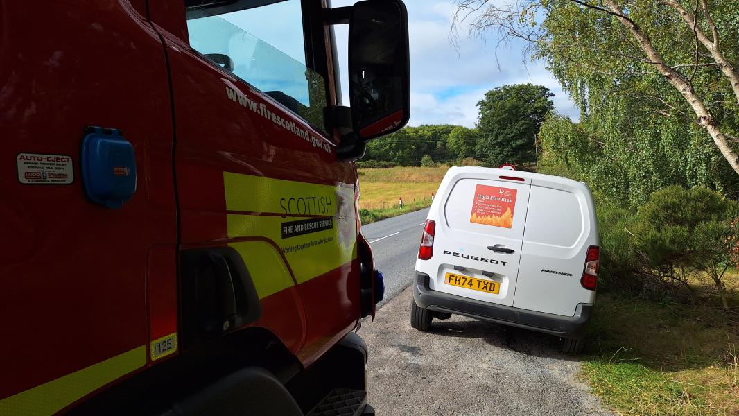 Part of a fire engine and the back of a white van