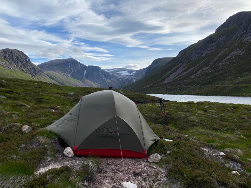 Tent next to Loch Avon with surrounding mountains.