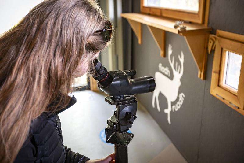 A person using a telescope through the viewpoint at RSPB Abernethy visitor centre.