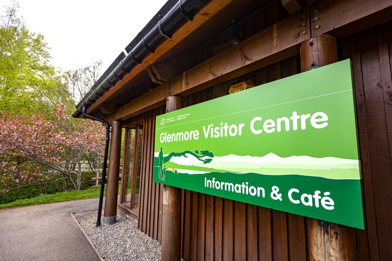 Large green sign on the side of the Glenmore visitor centre with the words, Glenmore visitor centre, information and café.