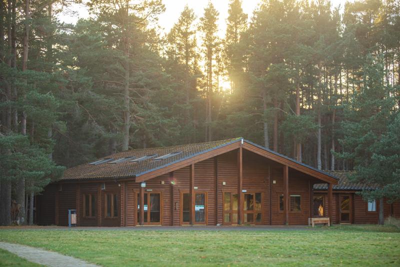 A large wooden building surrounded by trees, new dementia centre at Badaguish.