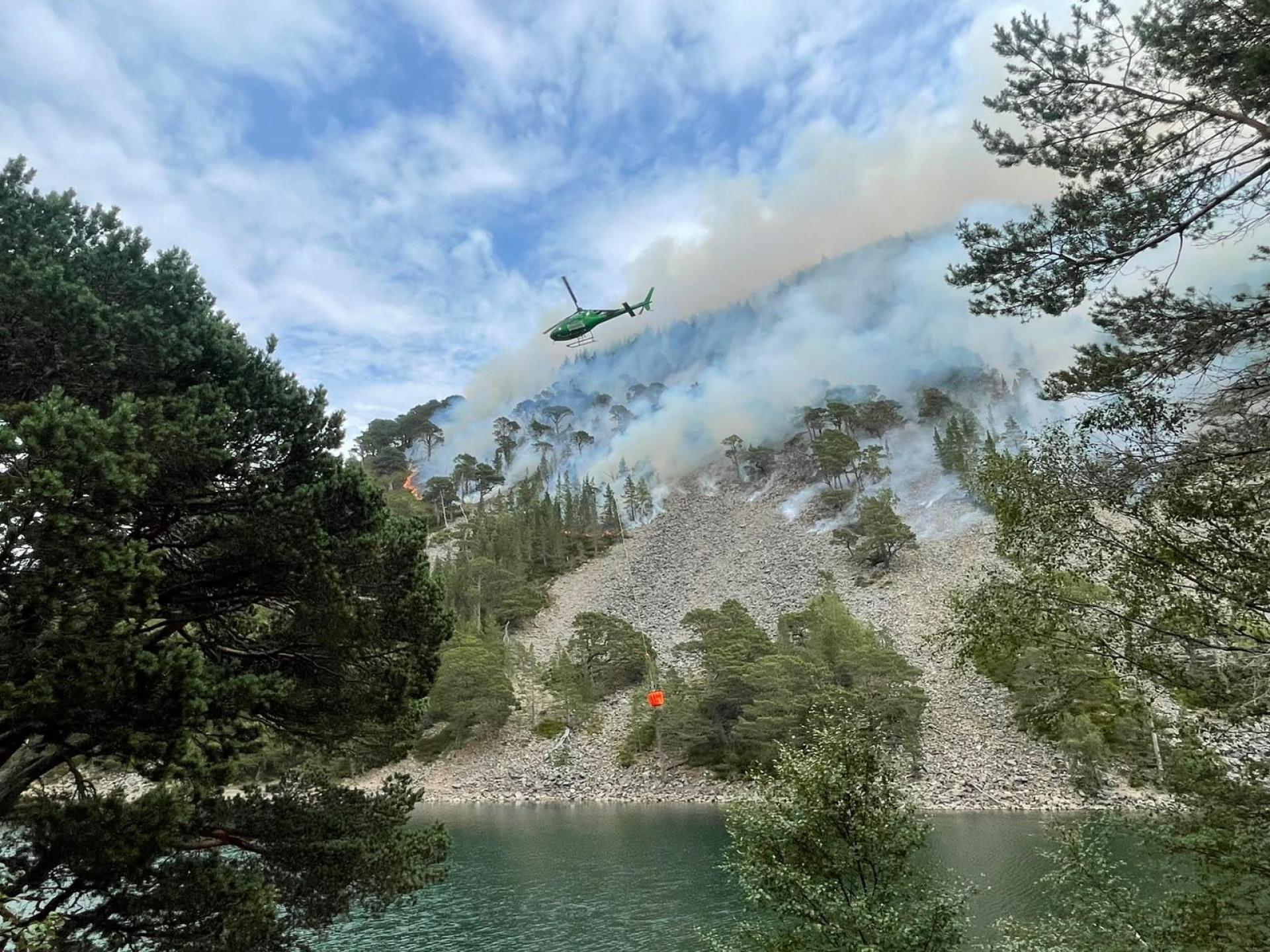 A helicopter with a large water bucket helps tackle a wildfire at the Green Lochan in the Cairngorms National Park