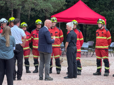 John Swinney talks to Area Commander Lynne Gow of SFRS, in front of a team of uniformed firefighters at Loch Morlich