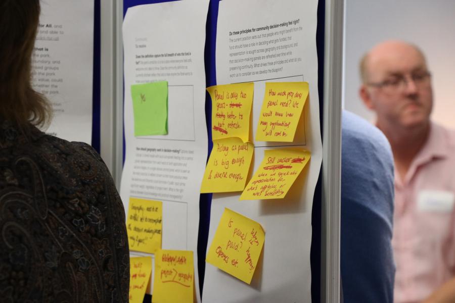 Person looking at notice board with hand written post-it notes attached.
