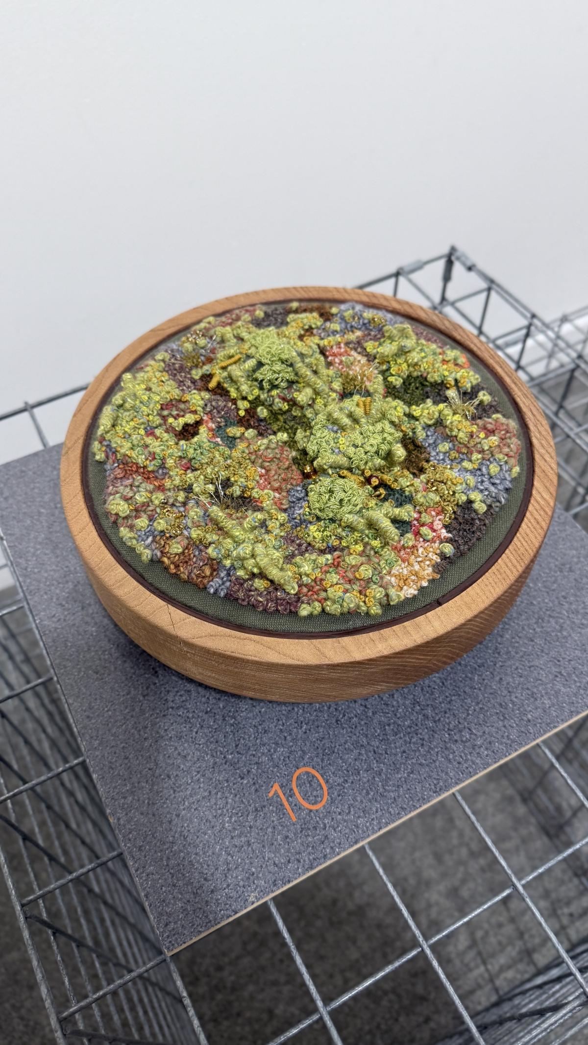 A pot with embroidered thread that looks like moss.