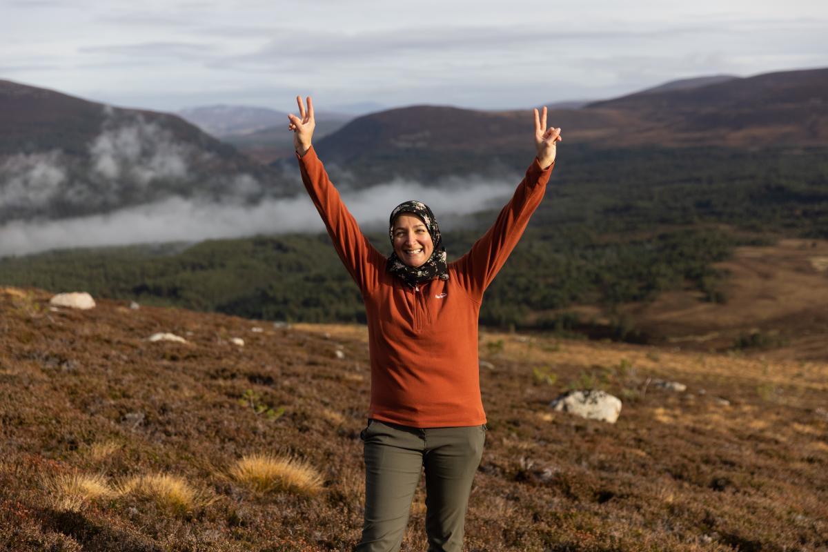 Person with arms in the air with valley in the background