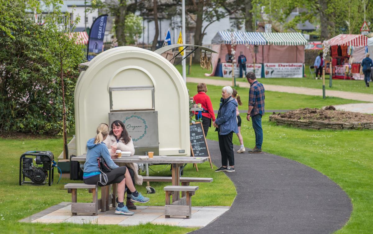 People sitting having coffee next to a food van