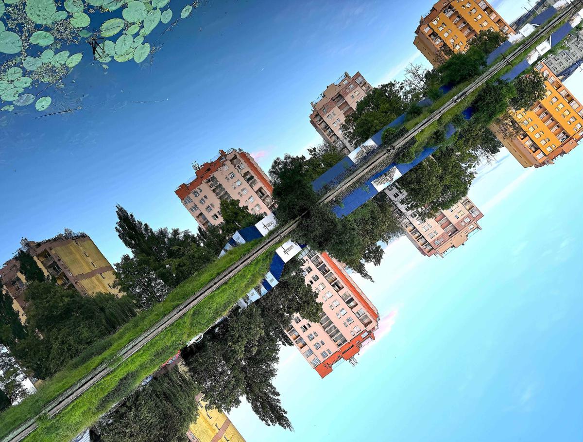 Tilted image of blocks of flats reflected in water.