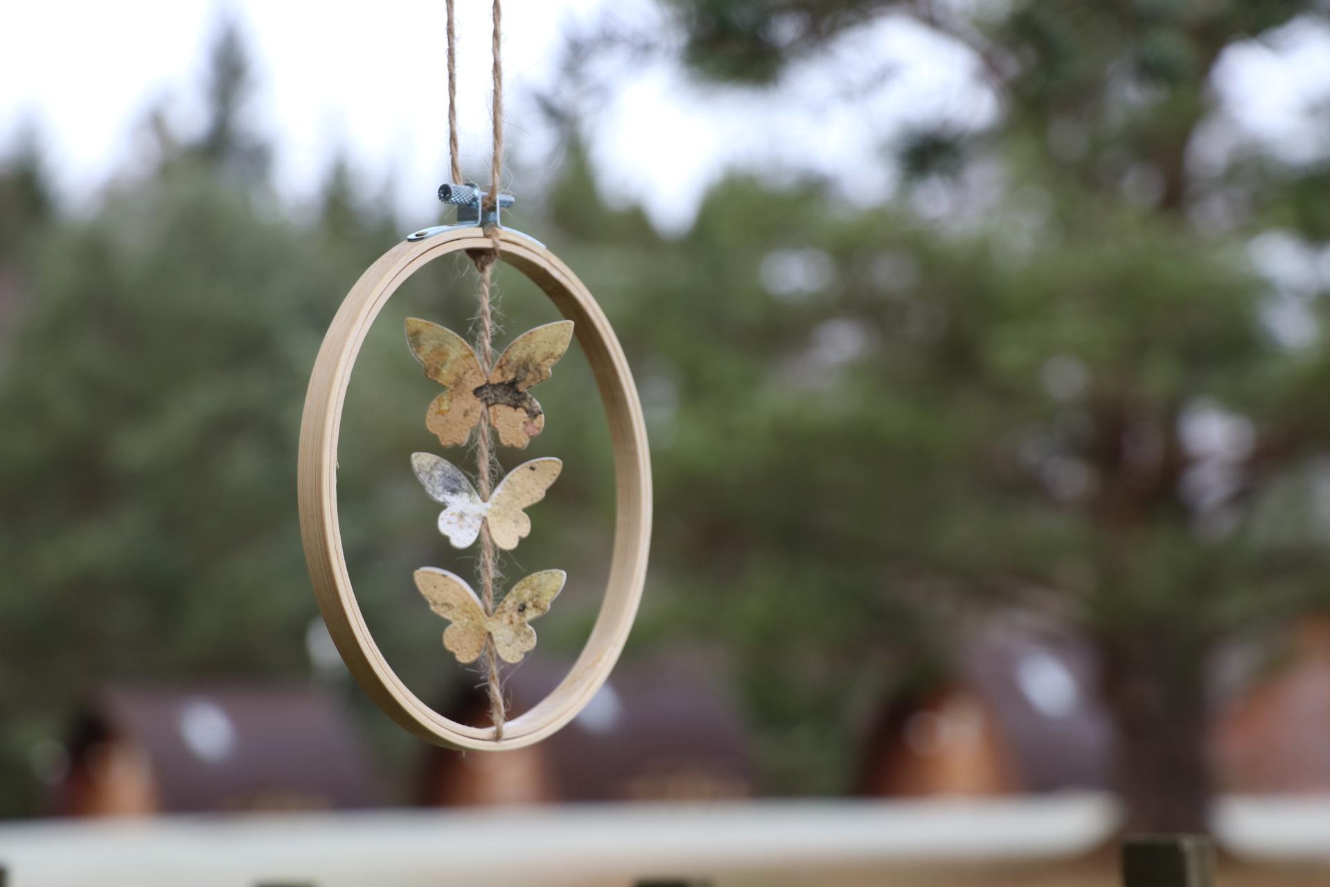 Three butterflies made of paper hanging in an embroidery hoop
