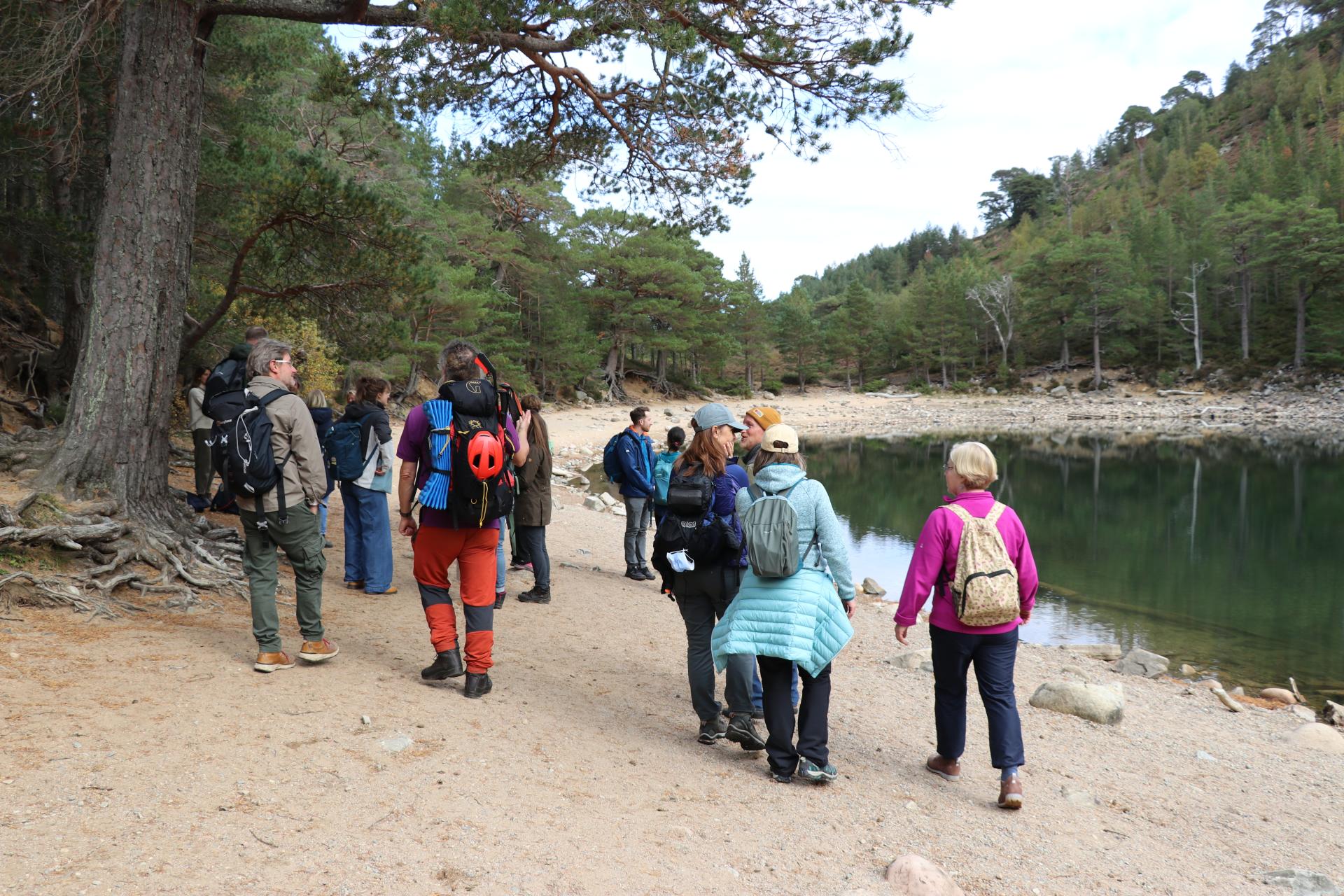 A group of people in walking gear next to a small loch.