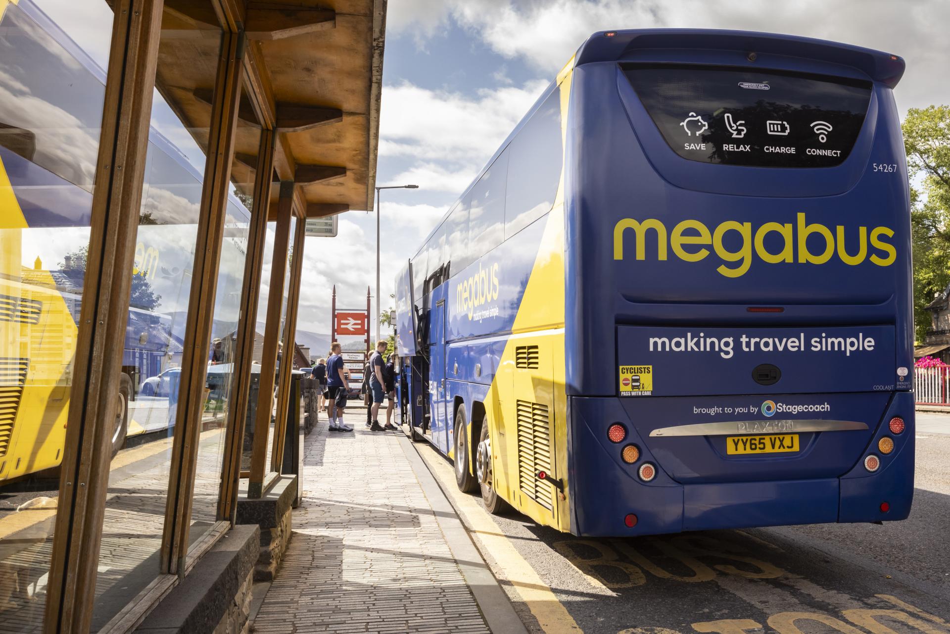 A large blue and yellow bus stopped at a bus stop
