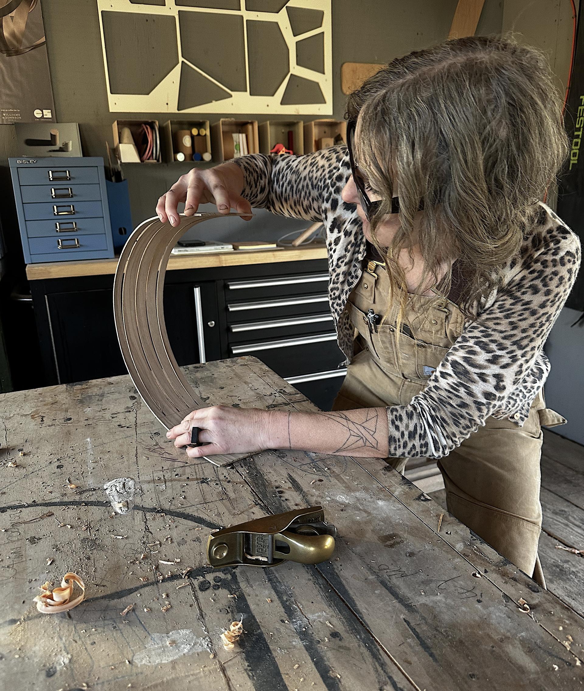 A person bending wood like material in a workshop