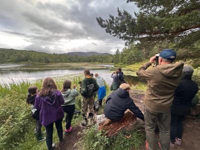 A group of people next to a loch looking for beavers