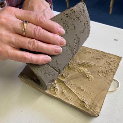 A hand pealing back a clay casting of foliage.