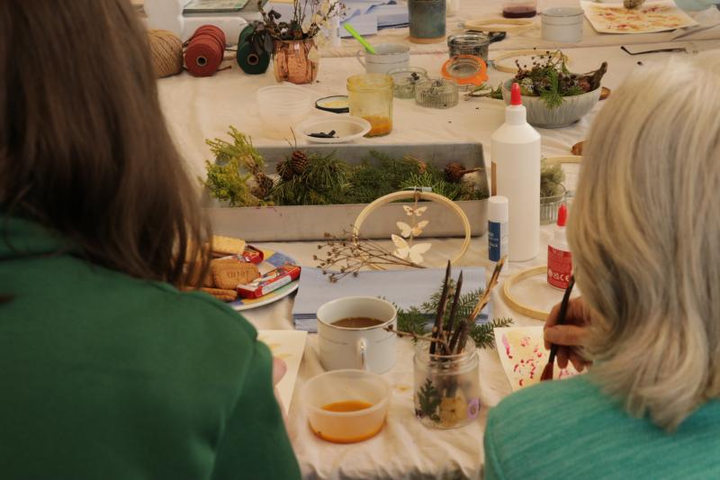 Two people sitting at a table with art supplies in front of them