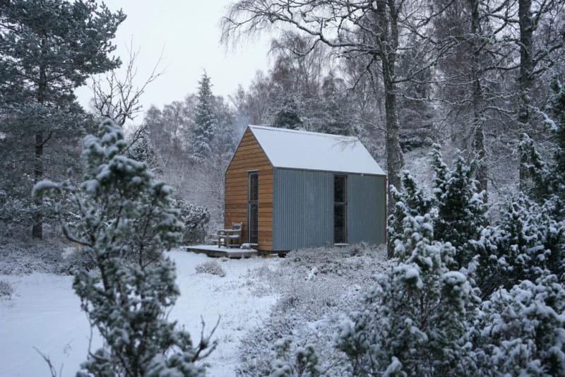 Image of Inshriach Bothy in snow covered woodland in the Cairngorms National Park.
