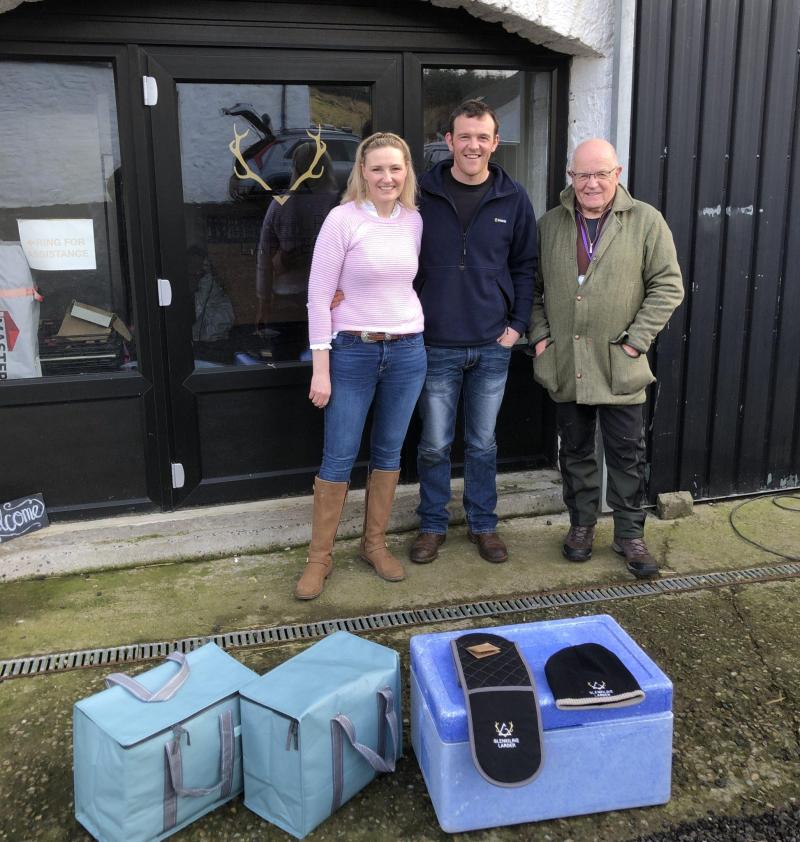 Three people standing in front of the deer larder with cold storage bags in foreground.