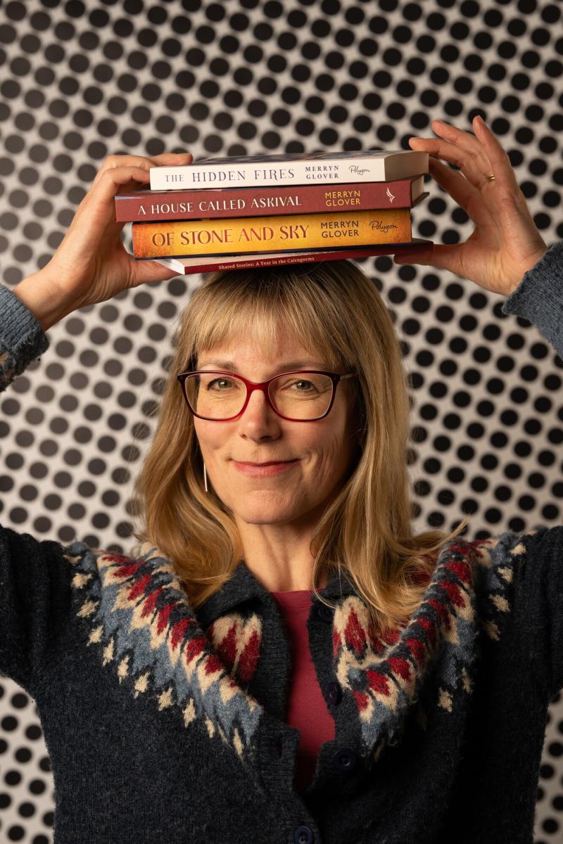 Female holding four books on top of their head.