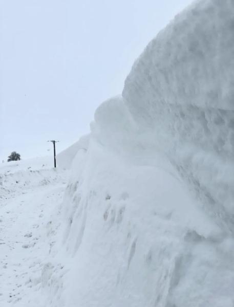 The side of a road in Glenbuchat with a wall of snow drifts 6ft high