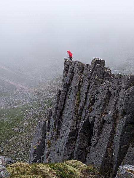 Mountain rescue volunteer on top of cliff during rescue of climbers