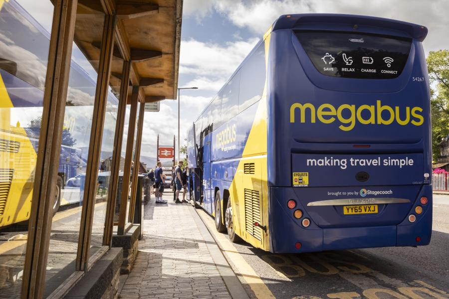 A large blue and yellow bus stopped at a bus stop