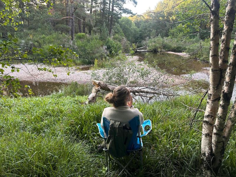 A person sitting in a chair next to a river