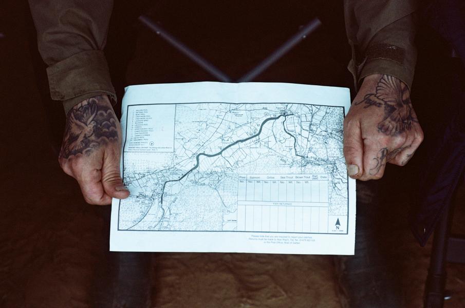 Picture taken from above of someone with tattooed hands holding a map.