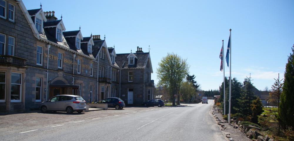 The Nethy Bridge hotel and main street under blue sky.