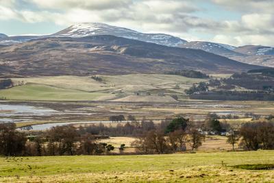 Views towards Ruthven Barracks with hills and snowy mountains in the distance.