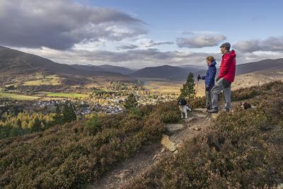 Two hillwalkers and their dogs enjoy the Braemar countryside.