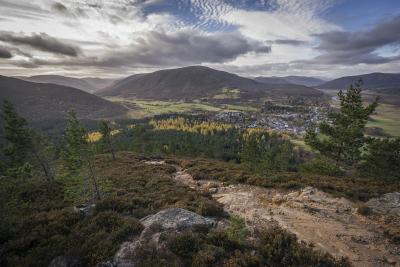 Mountain path looking down over forest on Braemar with surrounding hills.
