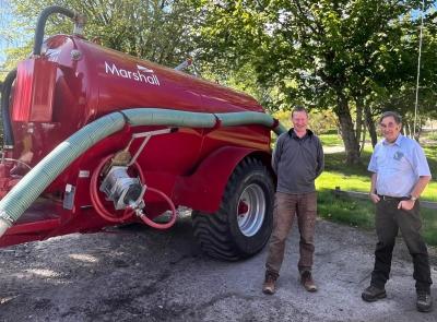 Two people standing to the right of a large red tanker