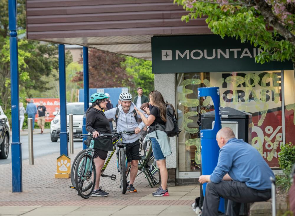 Three people chatting, two with bikes, on Aviemore main street.