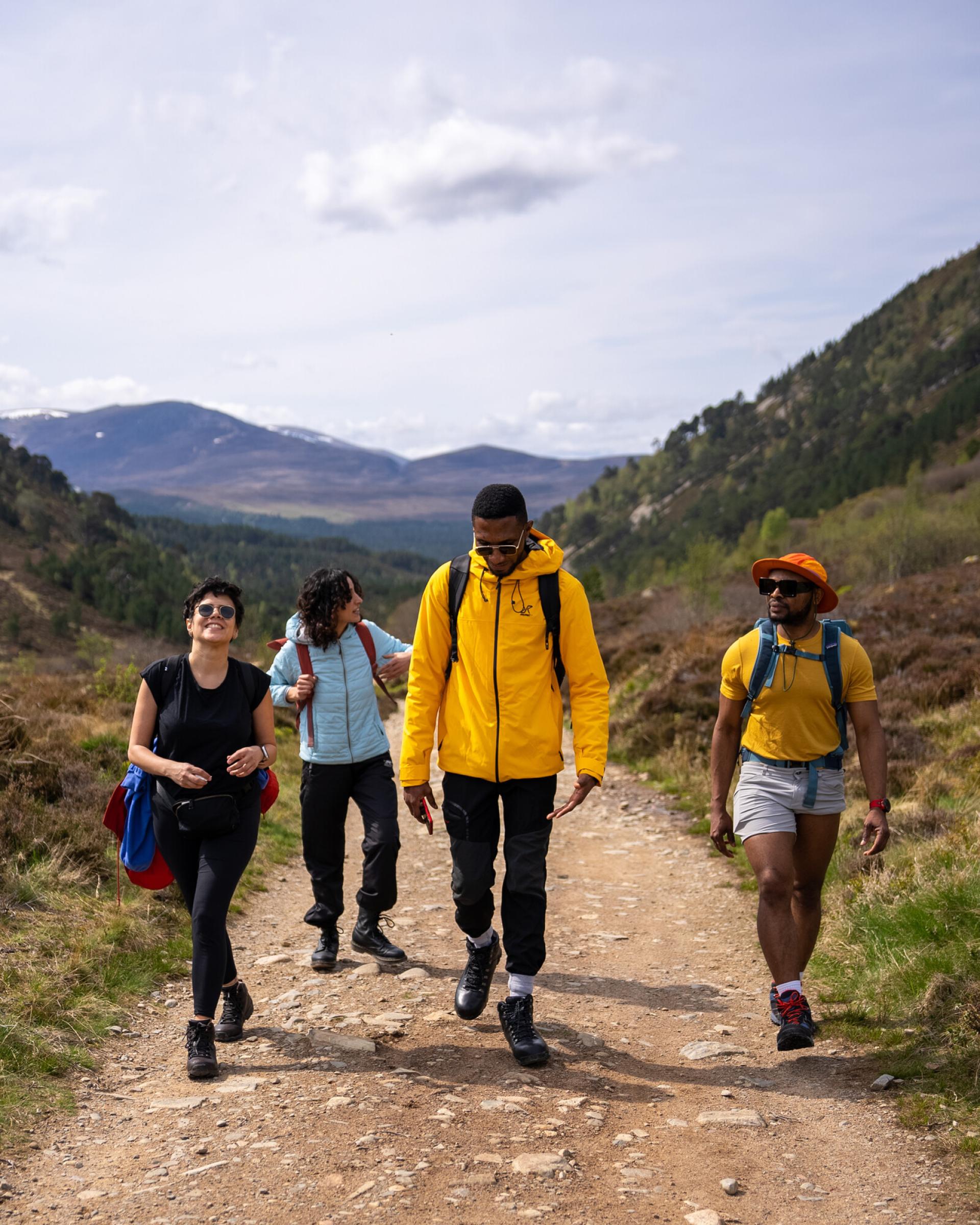 Four people on a hiking trail with mountains in the background