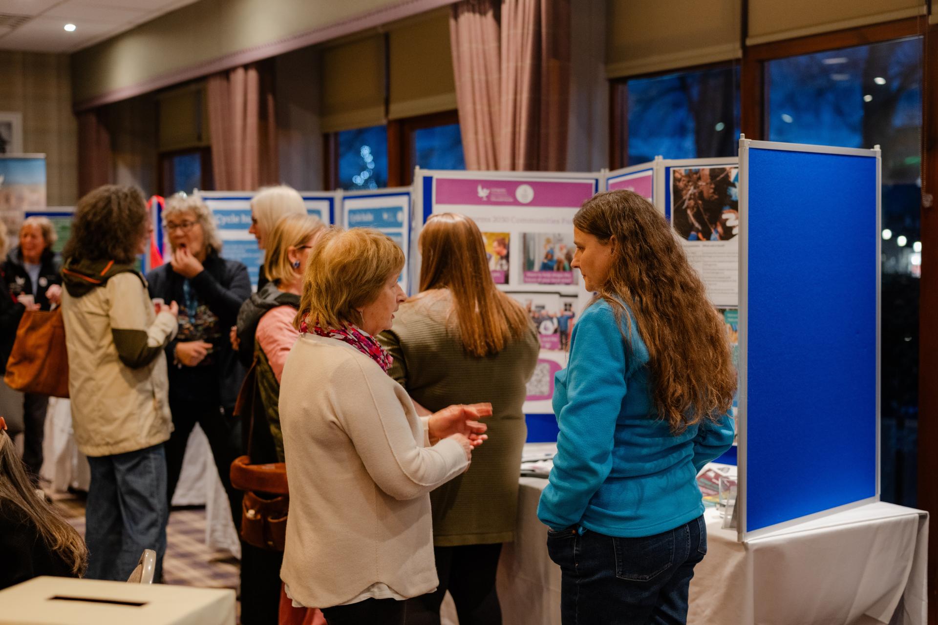 A group of people chatting in front of a display board at a Cairngorms National Park Authority event.