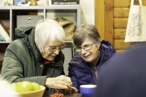 Two older women smile and examine some berries