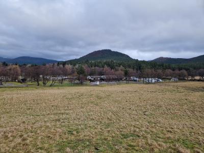 View of a field with trees, a caravan park and hills in the background.