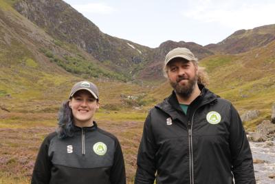Two rangers from Angus with mountains and river in background