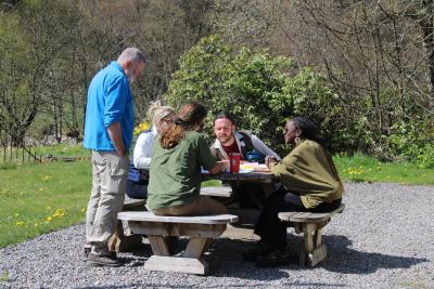 Five members of the public sit outdoors listening attentively